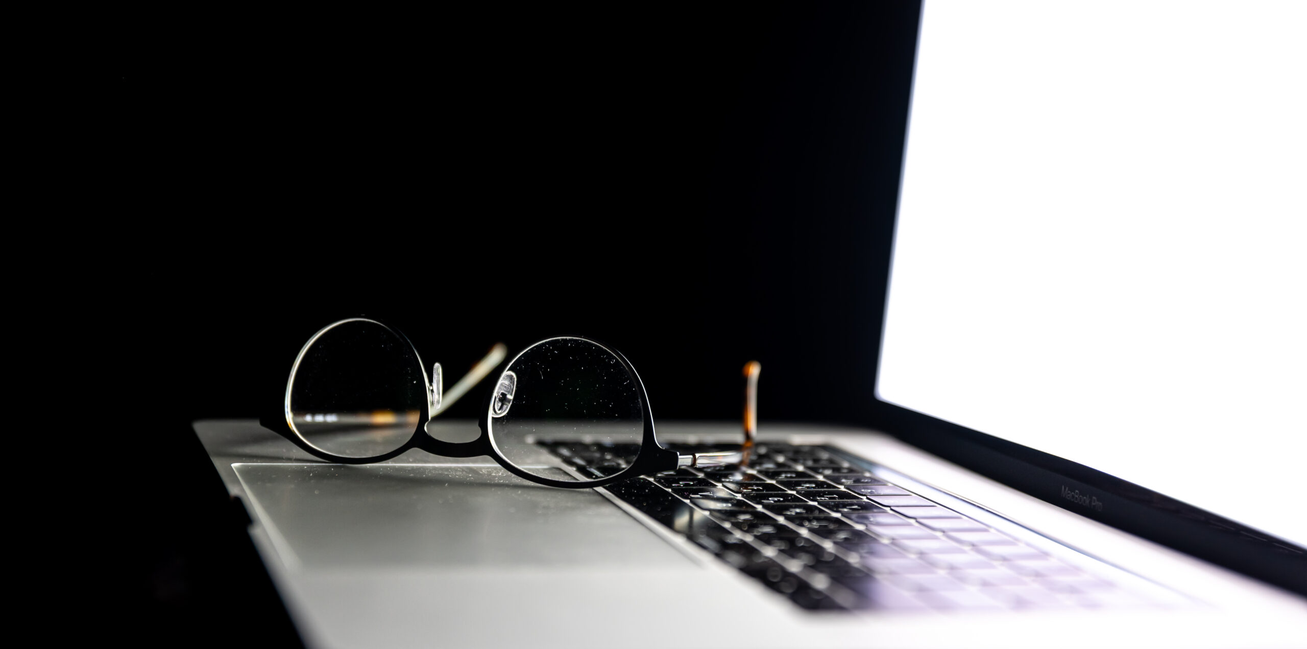 Close up of glasses on laptop in the dark.